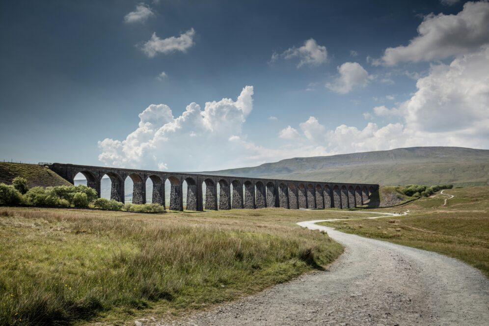 Stone viaduct spanning rural countryside path. 