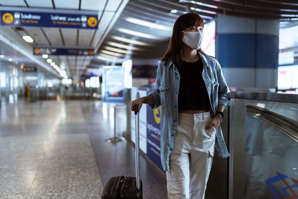 Woman with luggage walking through airport terminal.