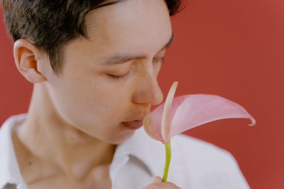 Person smelling pink flower gently.