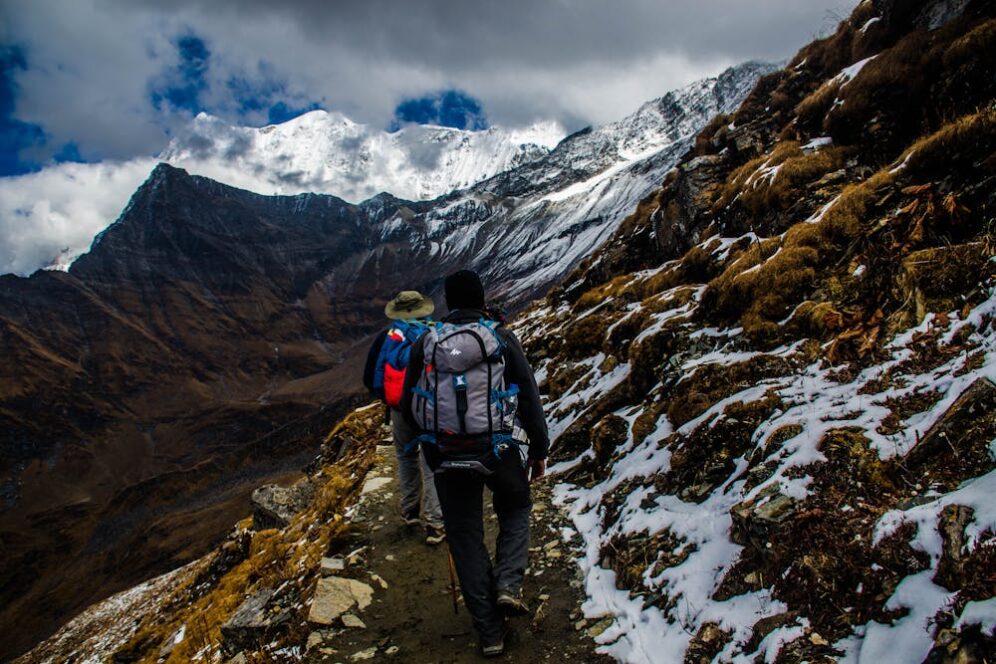 Hiker trekking snowy mountain trail with backpack.